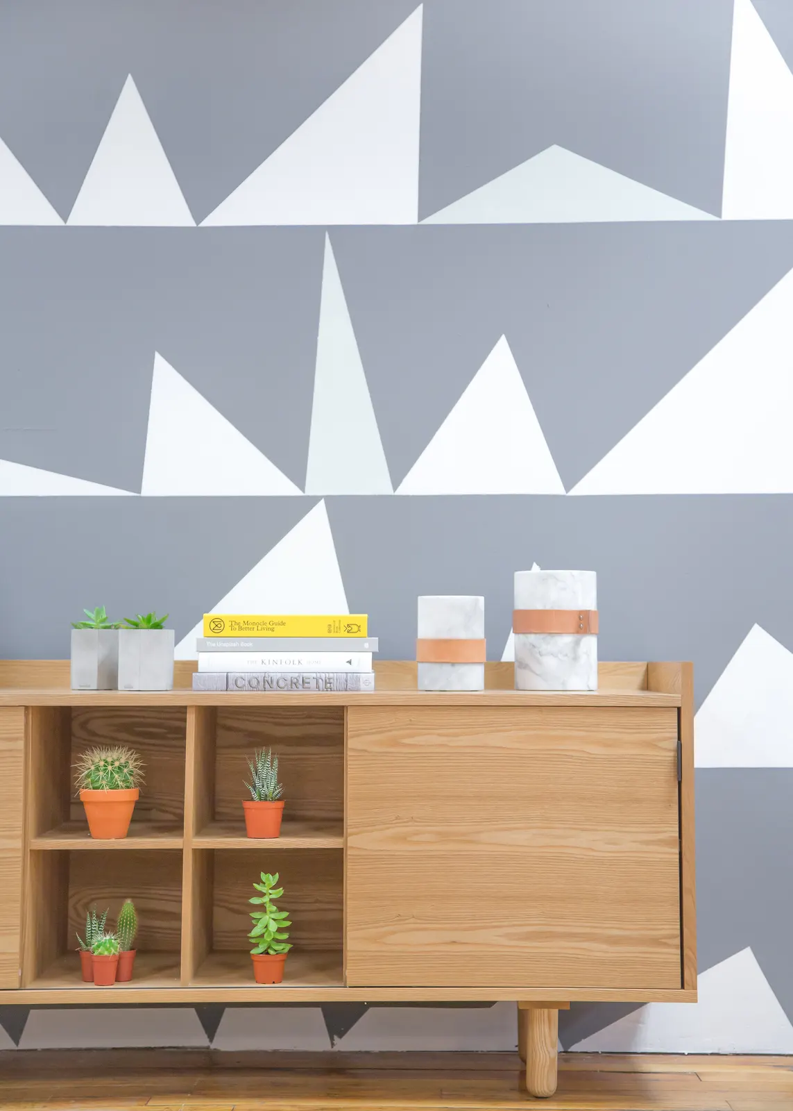 Tidy office sideboard with plants, books and marble organizers against a patterned wall